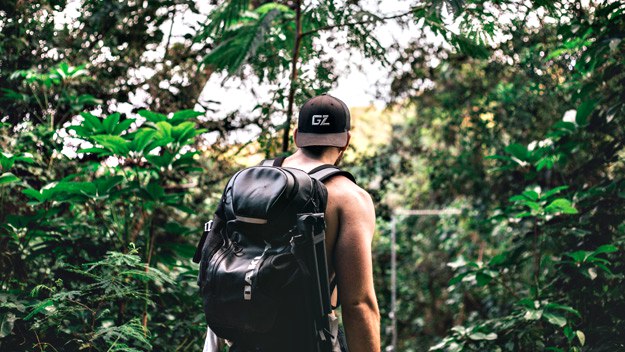 man wearing backpack in the forrest | Must Have Travel Items For Men To Survive Your Next Holiday Getaway