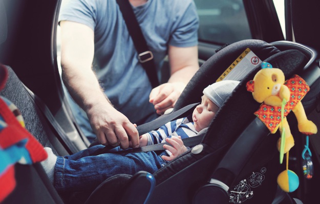 man putting baby seatbelt  | Fatherhood Guide for First Time Daddies | How To Be a Daddy