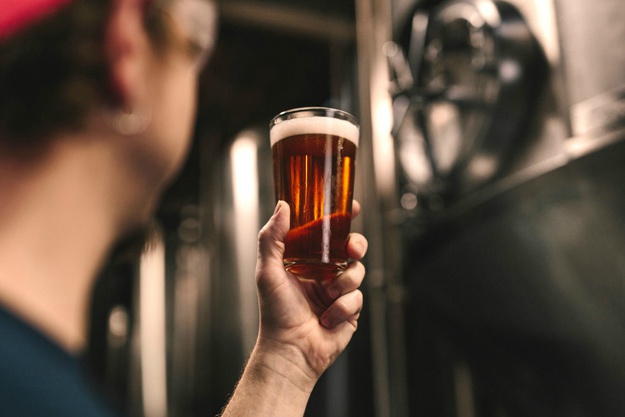 man holding glass of beer | Football Beer Drinking Guide By Team