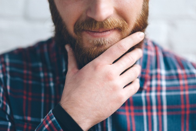 smiling man holding his beard | How To Trim Your Beard | Trimming Beard Tips