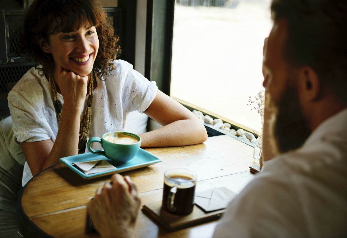 smiling woman sitting front of man near window