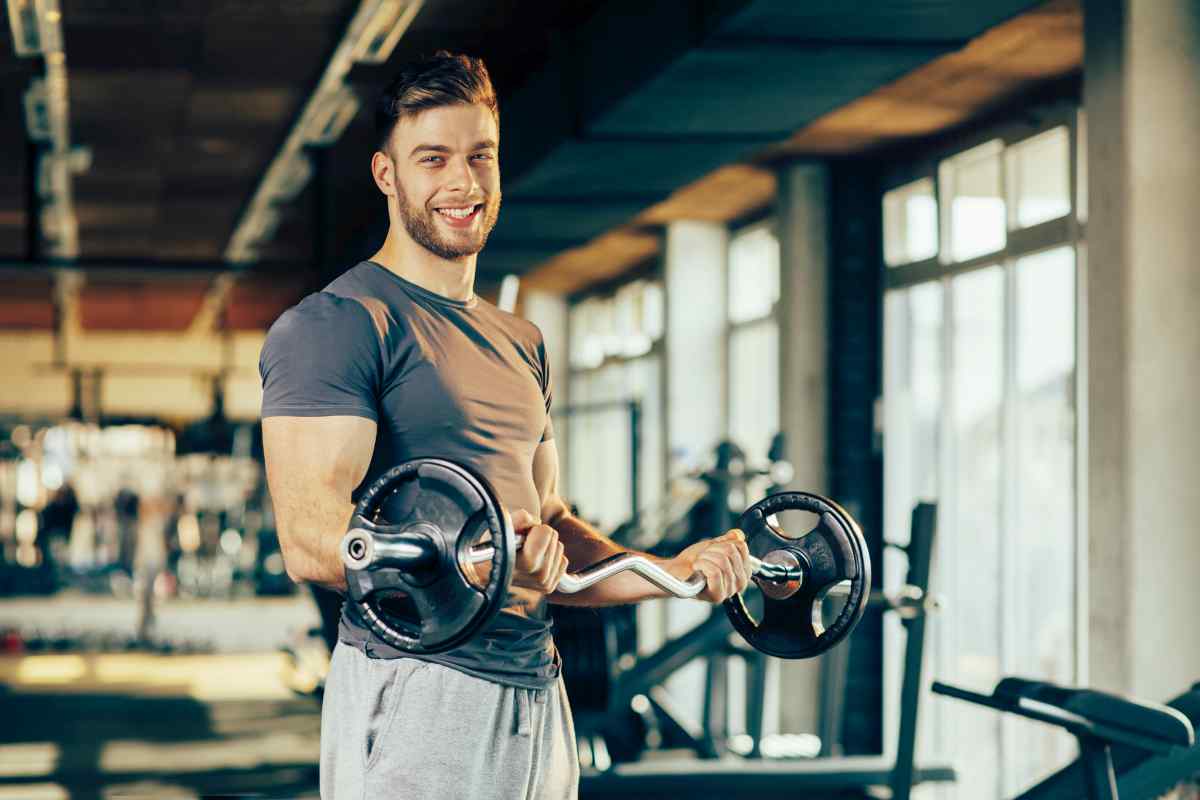 Handsome man doing biceps lifting in a gym | Ways To Reconnect With Your Manliness This New Year | become a better man
