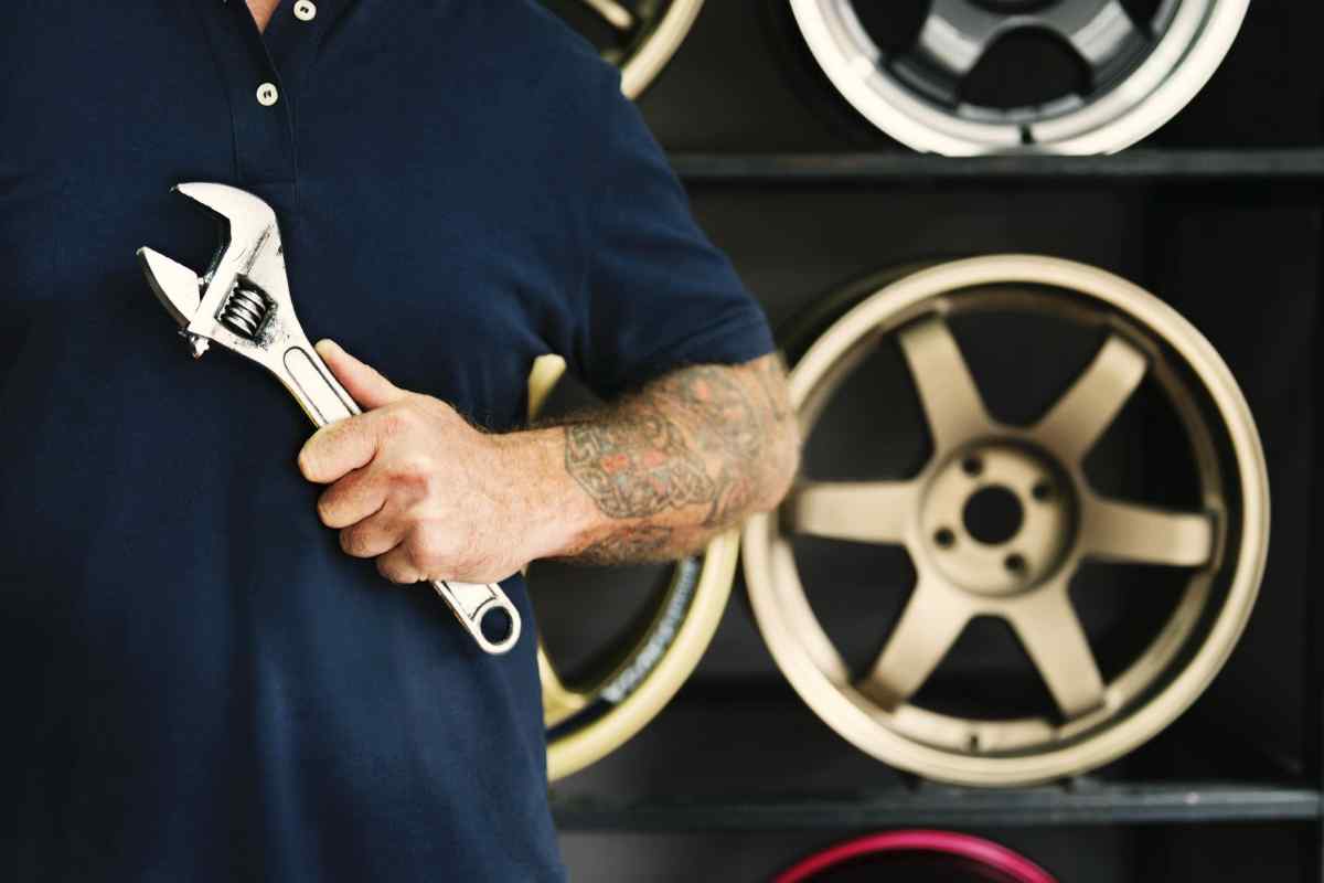 man holding silver crescent wrench behind vehicle wheels | Ways To Reconnect With Your Manliness This New Year | become a better man